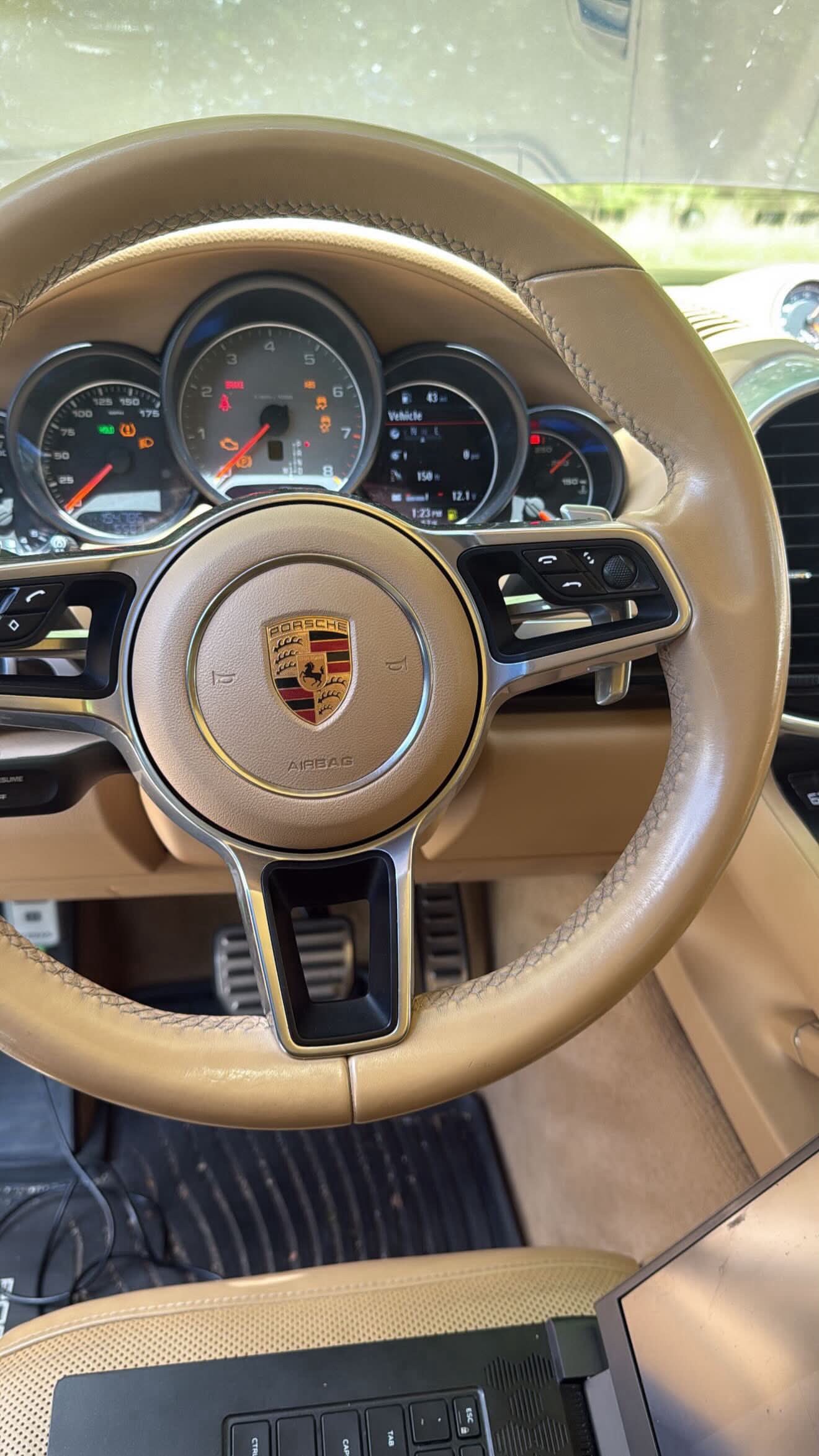 A Porsche steering wheel and gauge cluster with a diagnostic laptop at BMW Experts LLC